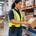 Worker wearing a Newland mobile terminal mountable case while handling a package at a warehouse workstation for shared device access.