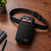 Ingenico POS payment terminal secured in an Agoz black waist belt holster displayed on a wooden tabletop.