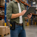 Warehouse employee carrying a Janam scanner grip while checking inventory