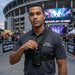 Security worker wearing chest harness pouch for Cobra two-way radio outside a concert venue